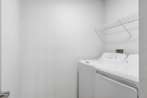 A white bed with a pillow and a white wall.