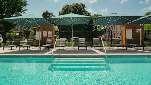 A pool with a ladder and umbrellas.