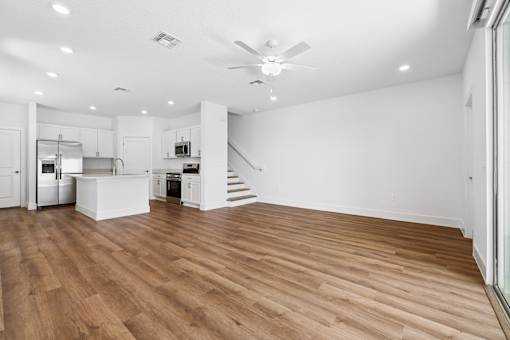 A spacious kitchen with wooden flooring and a ceiling fan.