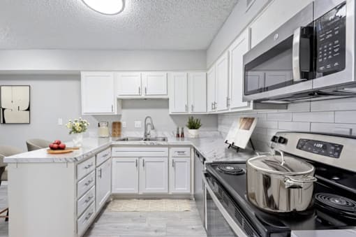 A modern kitchen with white cabinets and black appliances.