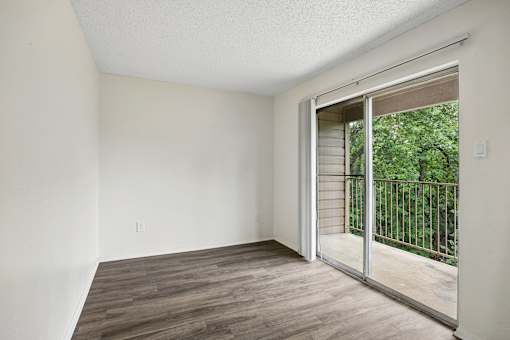 A room with a sliding glass door leading to a balcony.