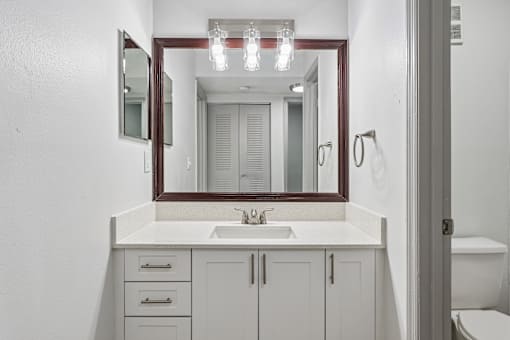 A bathroom with a sink, mirror, and cabinets.