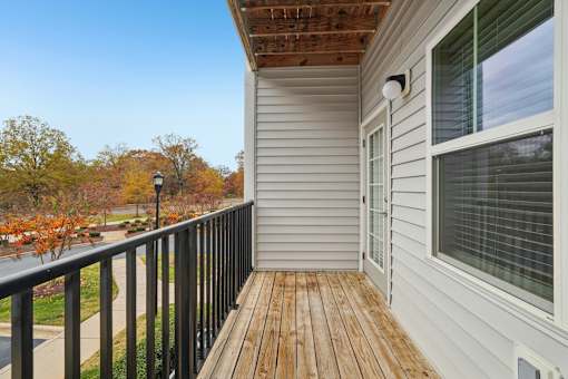 A balcony with a wooden floor and a black railing.
