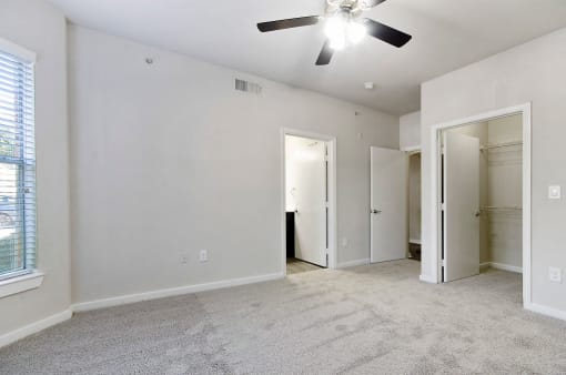 Bedroom with Large Walk-In Closet, Ceiling Fan, and Carpet