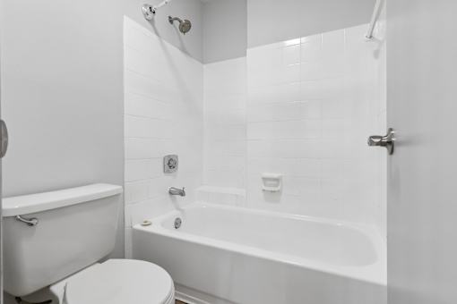 A white bathroom with a toilet, bathtub, and shower.