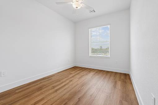 A room with a ceiling fan and a window with blinds.