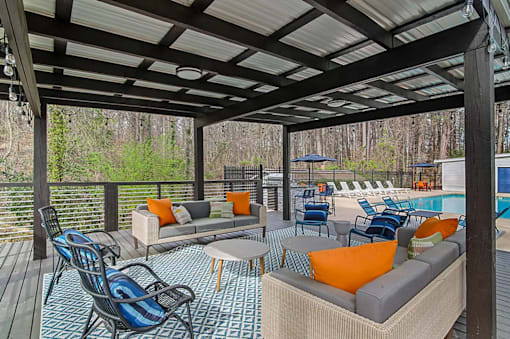 A covered deck with a pool and furniture.