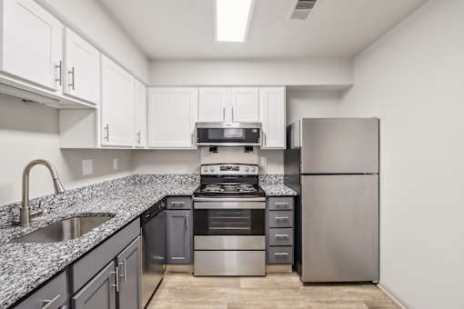 A kitchen with a stainless steel refrigerator, oven, and sink.
