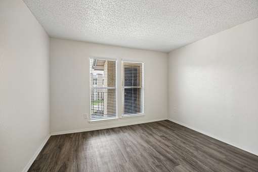 A room with a window and wooden flooring.