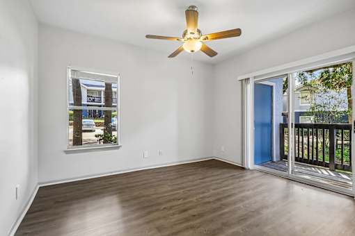 A room with a ceiling fan and sliding glass doors.