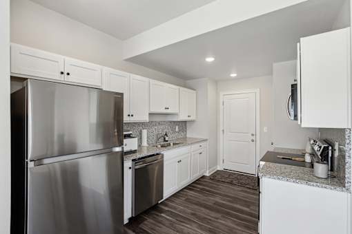 A kitchen with white cabinets and a stainless steel refrigerator.