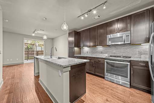 A modern kitchen with dark brown cabinets and a wooden floor.