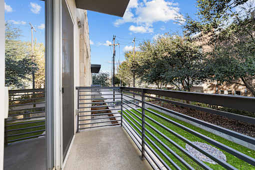 A balcony with a metal railing and a white painted symbol on the grass.