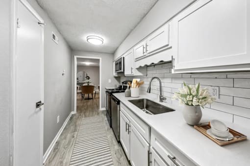 A kitchen with white cabinets and a striped rug.