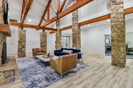 A living room with a stone fireplace and wooden beams.