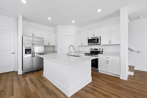 A modern kitchen with white cabinets and stainless steel appliances.