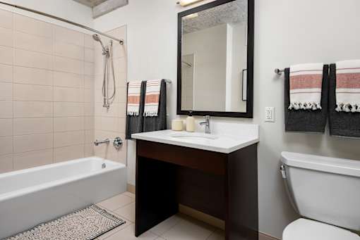 A bathroom with a white tub, sink, and towel rack.