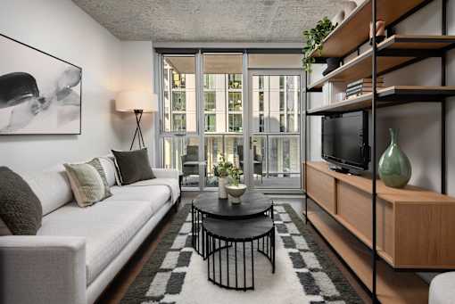 A living room with a white couch, a black coffee table, and a large window.