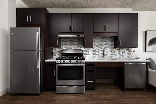 A modern kitchen with dark brown cabinets and stainless steel appliances.