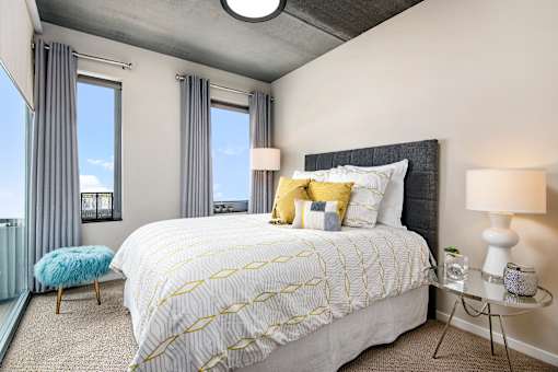 A bedroom with a large bed and a blue stool.