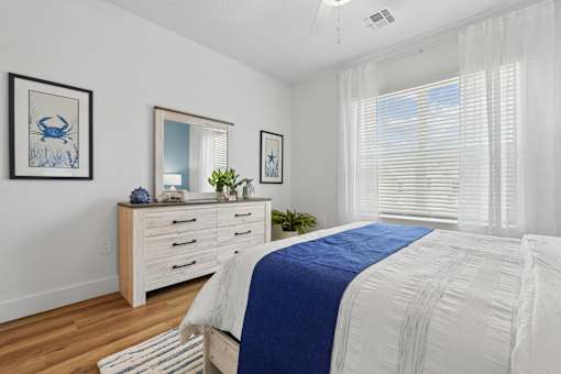 A bedroom with a bed, dresser, and two framed pictures on the wall.
