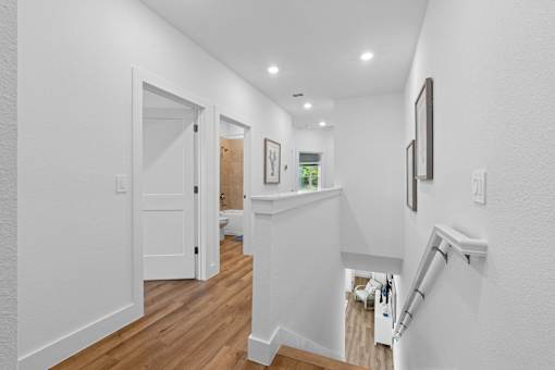 A white hallway with a staircase and a door.