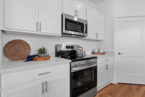 A modern kitchen with white cabinets and a black stove top.