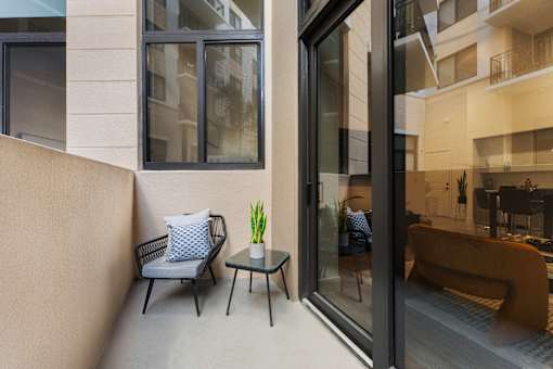 A balcony with a chair and a table with a plant on it.