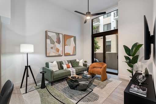 A living room with a green couch, a black coffee table, and a painting on the wall.