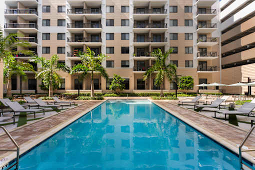 A large swimming pool in front of a multi-story apartment building.