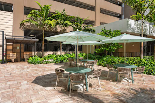 A patio with tables and chairs and umbrellas.