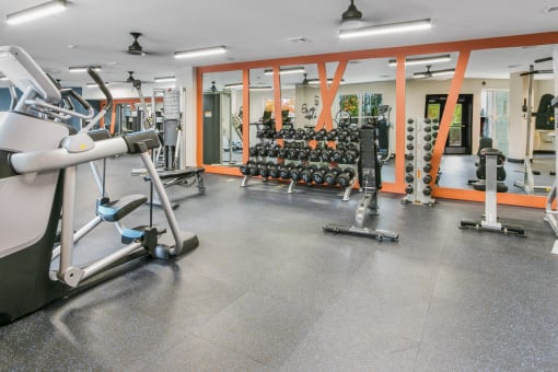 a gym with weights and cardio equipment in a building with orange walls