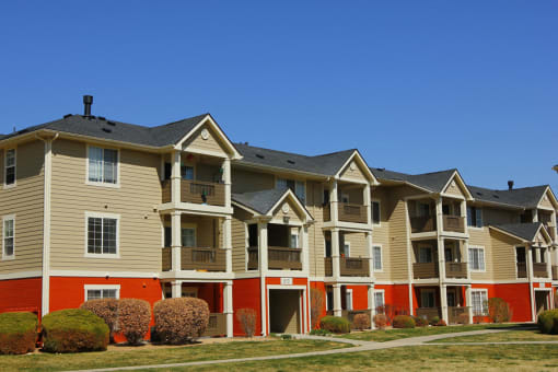 Ardenne Apartment Building with beigh and blue paint, green grass, and bright blue skies