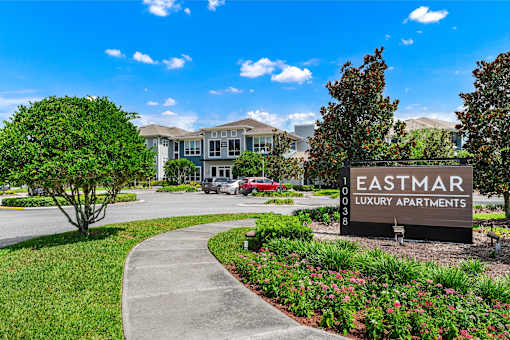 A sign for Eastmar Luxury Apartments is in front of a building and some trees.