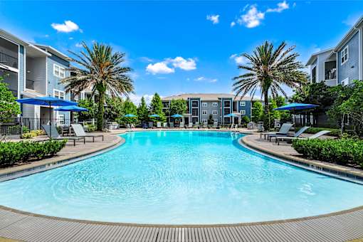 A large swimming pool surrounded by palm trees and lounge chairs.