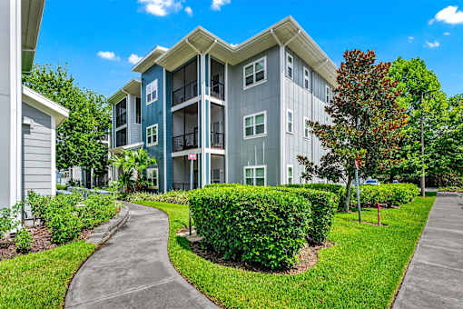 A modern apartment building with a well-maintained lawn and walkway.