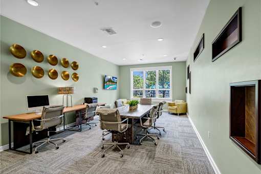 A conference room with a long table and chairs, a television, and a view of trees outside the window.