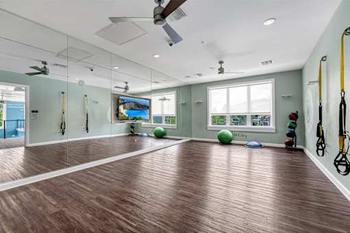 A gym with wooden floors and exercise equipment.