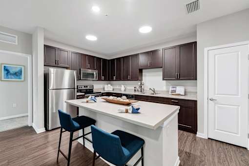A kitchen with a white island and blue chairs.