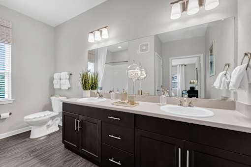 A bathroom with a white toilet and a large mirror above a sink.