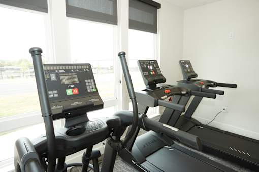 Two treadmills with digital displays in a bright room.