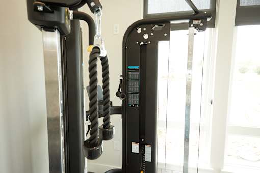 A black gym machine with a digital display and a cable attached to it.