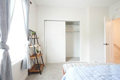 A room with a bed, a shelf, and a window.
