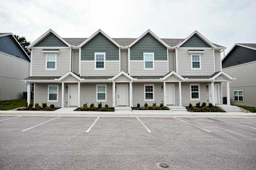 A row of houses with a parking lot in front.