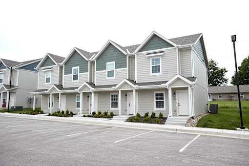 A row of houses with a parking lot in front.