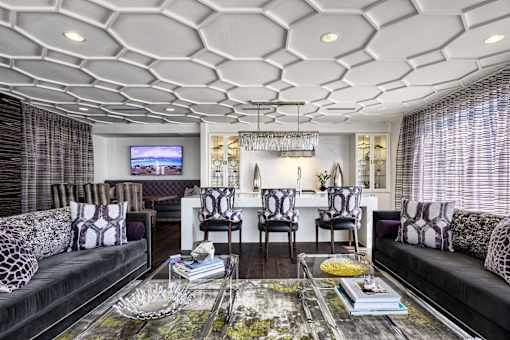 A living room with a black couch and a glass coffee table.