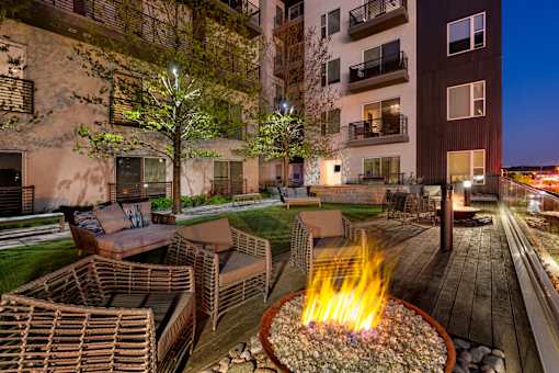A fire pit in the middle of a patio surrounded by chairs.