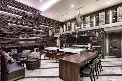 A modern kitchen with a dark wood finish and a long island with chairs.