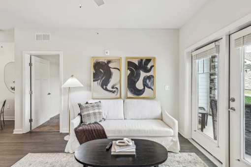 a living room with a white couch and two paintings on the wall