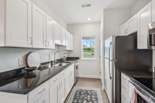a white kitchen with white cabinets and black counter tops